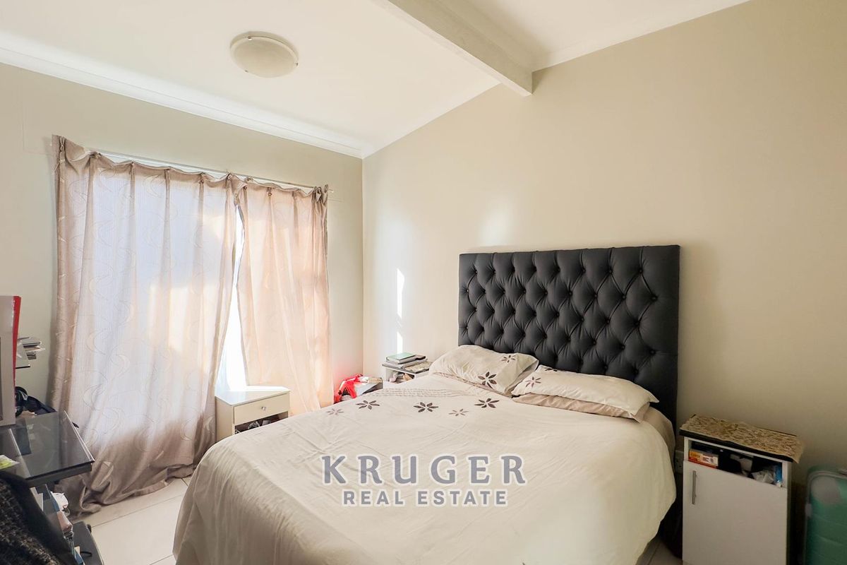 A bedroom featuring tiled flooring, neutral wall finishes, and a large window with curtain tracks.