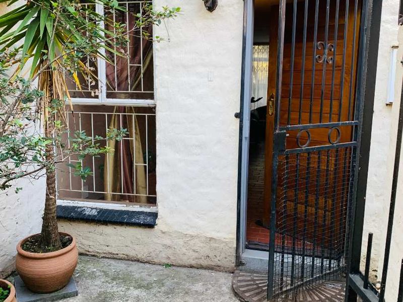 A small rear courtyard area featuring a concrete patio, security gate, and security bars on the window.