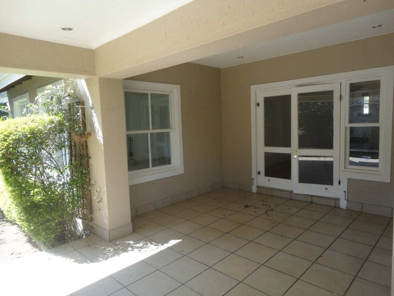 A covered patio area featuring tiled flooring, recessed lighting, and direct access to the interior through double glass doors and sash windows.