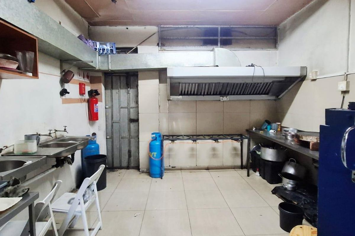 Commercial kitchen space featuring stainless steel sinks, a large extractor hood, tiled surfaces, and gas infrastructure for professional food preparation.