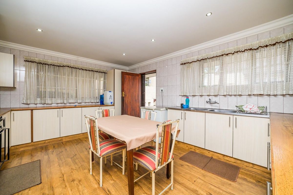 A functional kitchen featuring laminate cabinetry, tiled splashbacks, and laminate flooring, offering a practical layout with ample counter space.