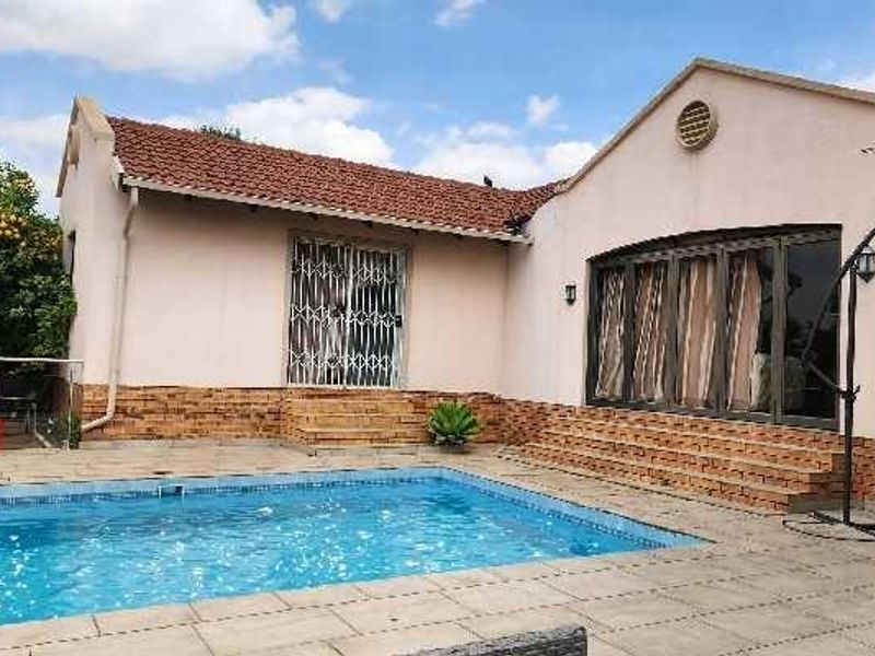 Rear exterior view featuring a swimming pool, paved patio area, and direct access to the home via sliding doors and security gates.