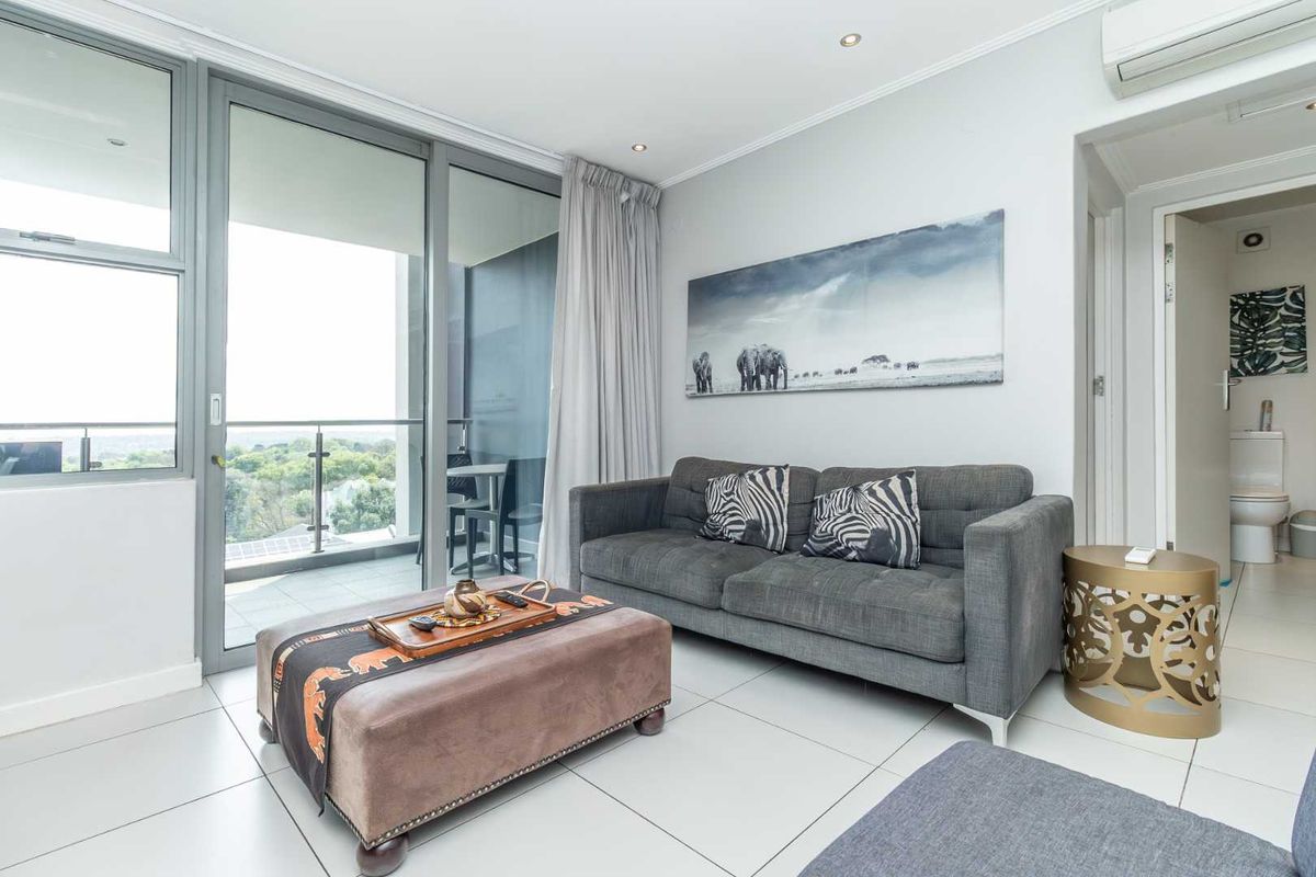 Modern living room featuring large sliding glass doors leading to a private balcony, tiled flooring, and a wall-mounted air conditioning unit.