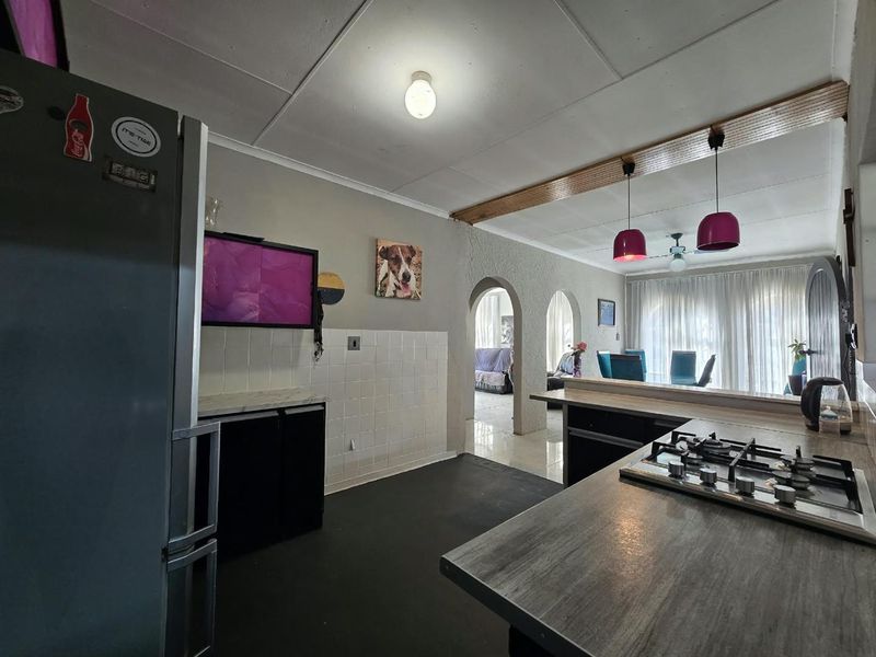 Open plan kitchen and dining area featuring a gas hob, tiled splashback, and distinctive architectural archways leading to the adjacent living space.