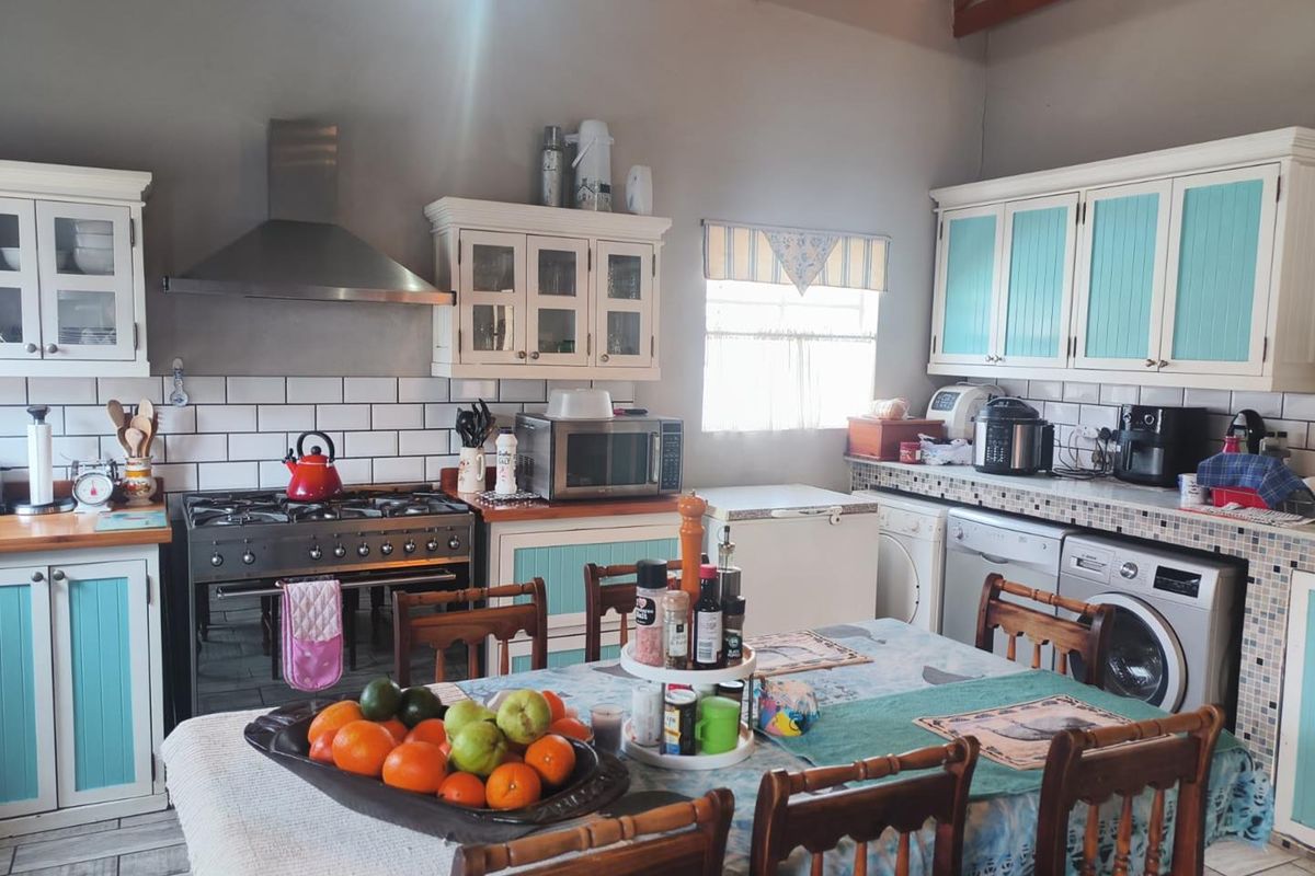 A functional kitchen featuring built-in cabinetry, a gas stove with extractor fan, subway tile backsplash, and exposed timber ceiling beams.