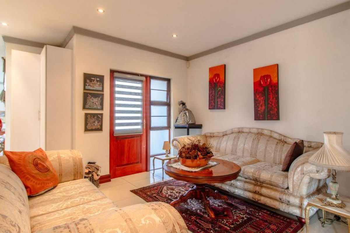 A comfortable living room featuring tiled flooring, recessed ceiling lighting, and a wooden door with glass panels providing access to the exterior.