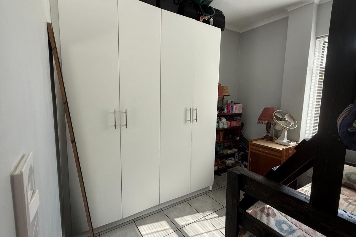 A bedroom featuring built-in white cabinetry and tiled flooring, providing functional storage space within the room.