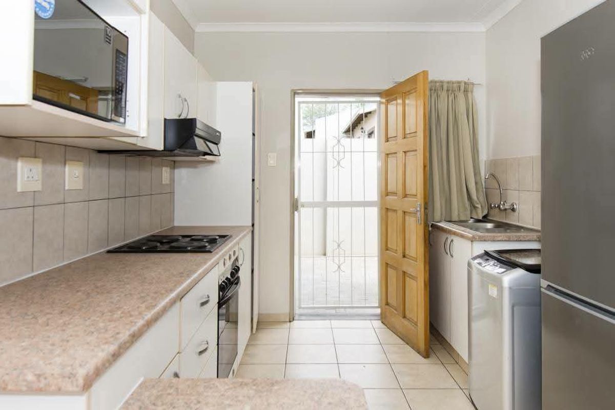 Functional kitchen featuring built-in cabinetry, electric hob, oven, and direct access to an exterior area through a security gate.