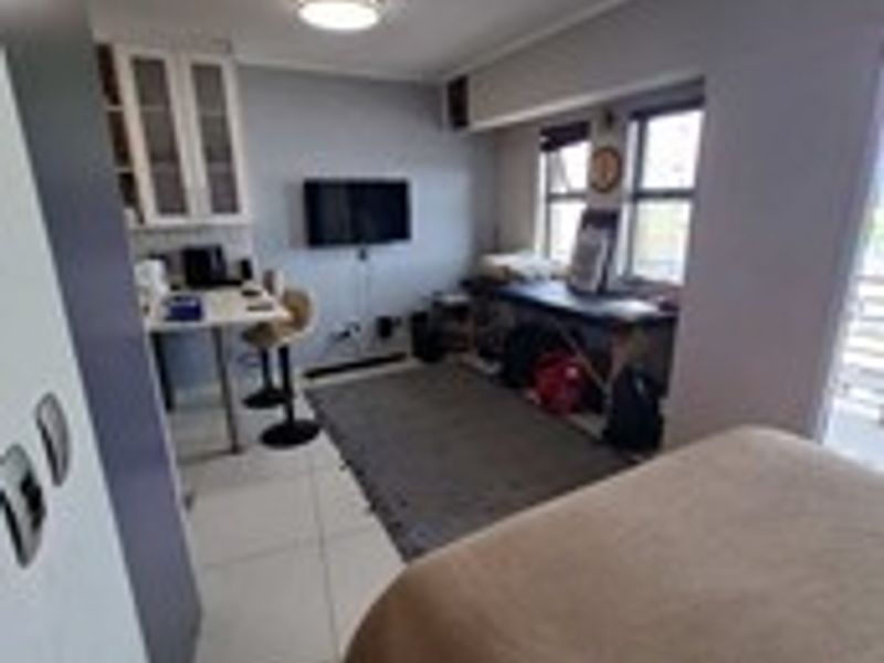 An open-plan studio apartment featuring tiled flooring, built-in cabinetry, and natural light from the window.