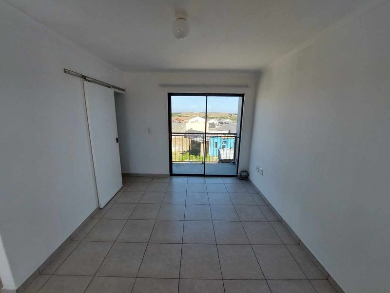 An empty bedroom featuring tiled flooring, a sliding door leading to a balcony, and a built-in cupboard.