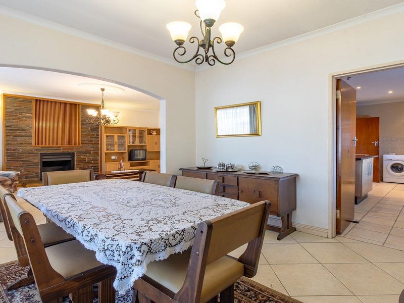 Open plan dining and living area featuring tiled flooring, a stone fireplace, and direct access to a separate laundry space.