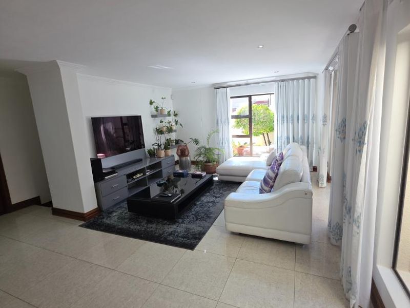 A bright and spacious living room featuring large format floor tiles, recessed lighting, and expansive sliding glass doors that provide ample natural light.
