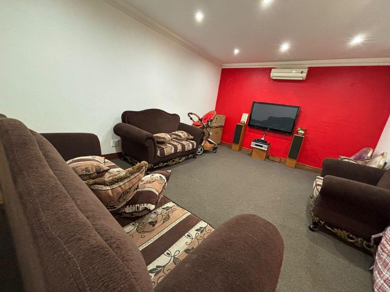A living room featuring carpeted flooring, recessed downlighting, and a wall-mounted split-system air conditioning unit.