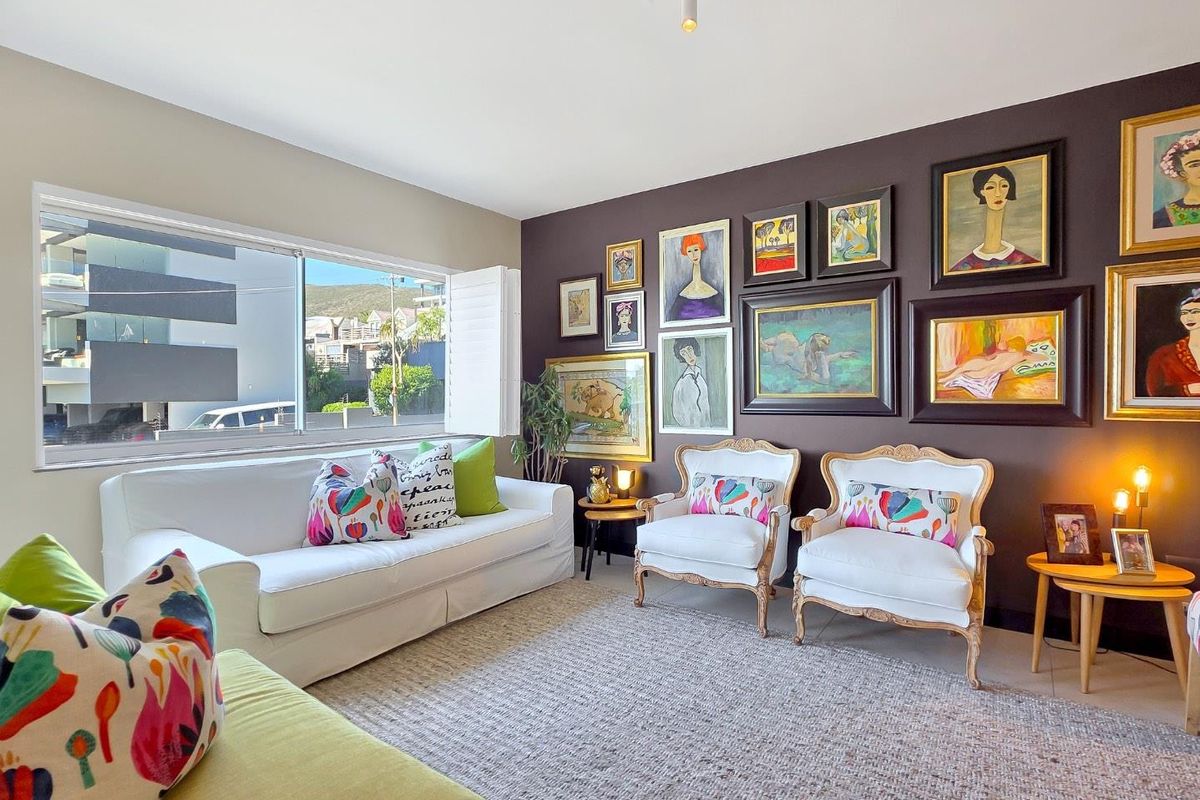A well-maintained living room featuring a large window, neutral tiled flooring, and a dark accent wall.
