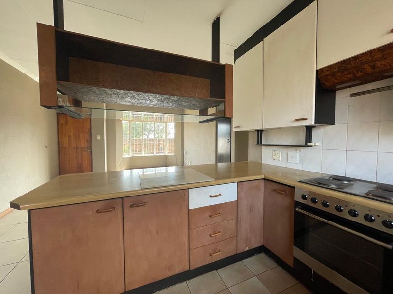 A dated kitchen featuring built-in cabinetry, laminate countertops, and an integrated electric stove and oven, offering potential for a modern renovation.