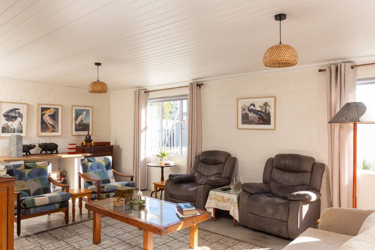 A bright living room featuring painted brick walls, a tongue-and-groove ceiling, and large windows that provide ample natural light.