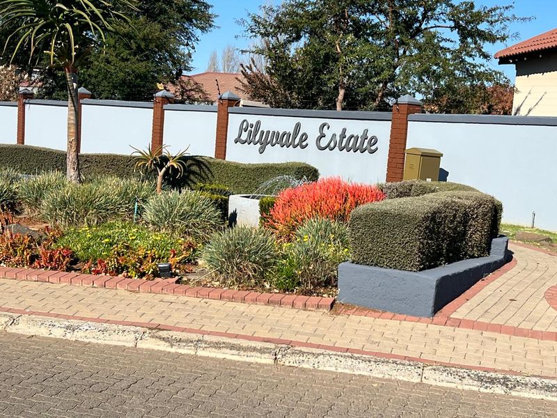 The entrance to Lilyvale Estate featuring a well-maintained boundary wall, professional landscaping, and a decorative water feature.