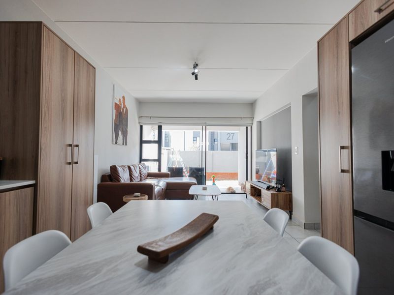 Modern open-plan living area featuring tiled flooring, built-in cabinetry, and a sliding glass door leading to an outdoor space.