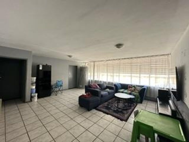 Spacious living area featuring tiled flooring and a large window with blinds, offering a blank canvas for potential interior updates and modernization.