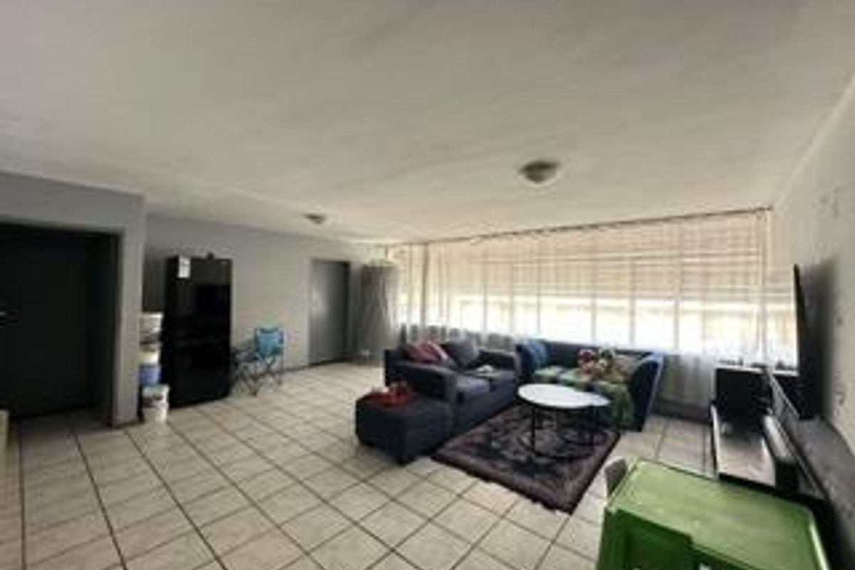 Spacious living area featuring tiled flooring and a large window with blinds, offering a blank canvas for potential interior updates and modernization.