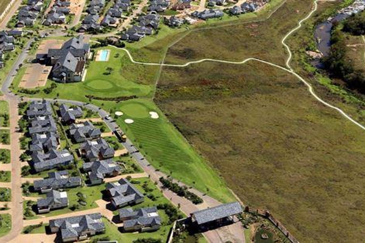 Aerial view of a residential estate featuring landscaped grounds, a golf course, and surrounding natural greenbelt areas.