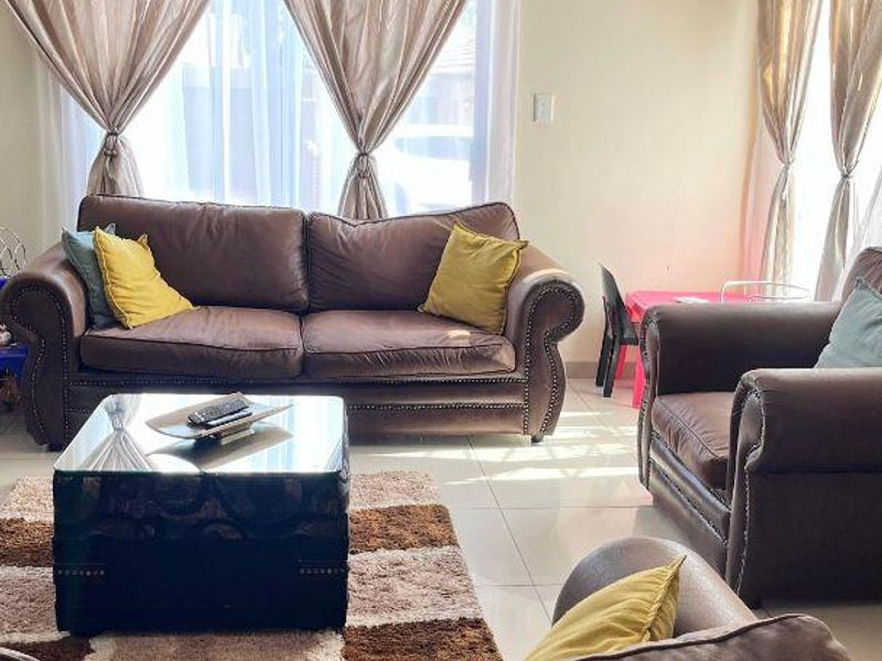 A bright living room featuring tiled flooring and natural light, providing a comfortable and functional space for relaxation.
