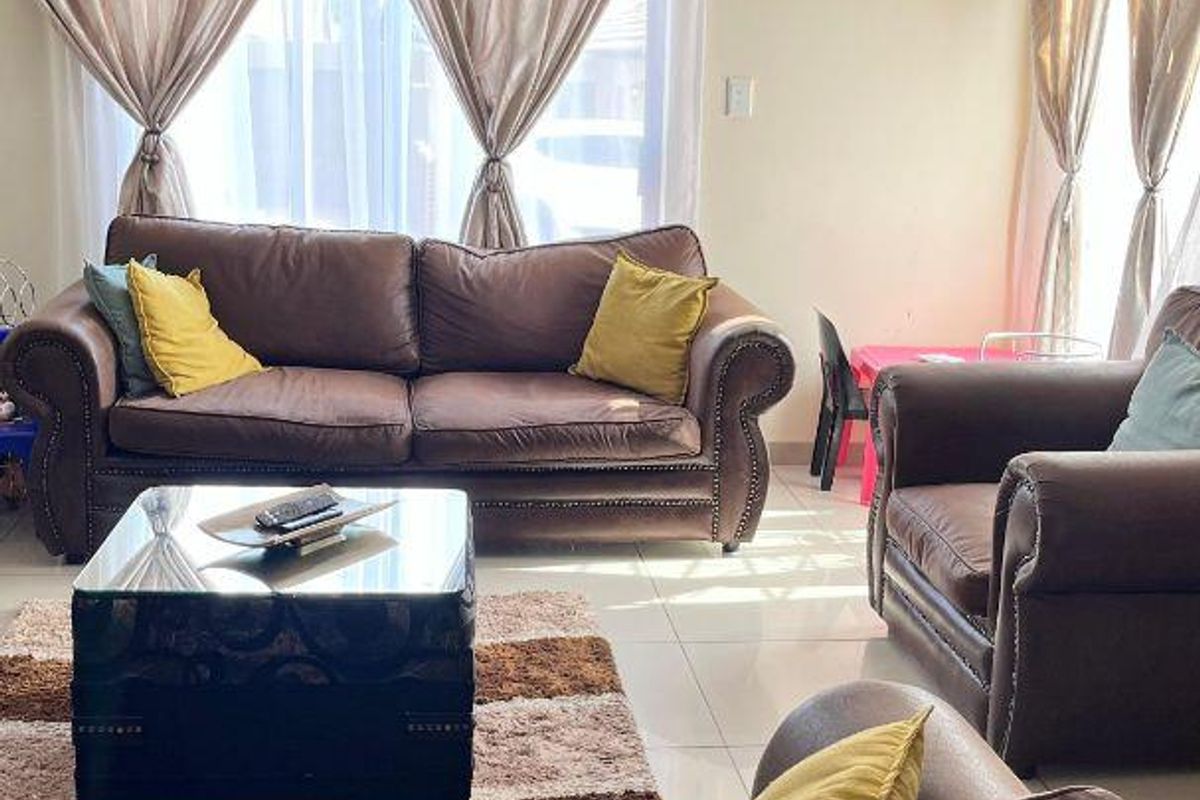 A bright living room featuring tiled flooring and natural light, providing a comfortable and functional space for relaxation.