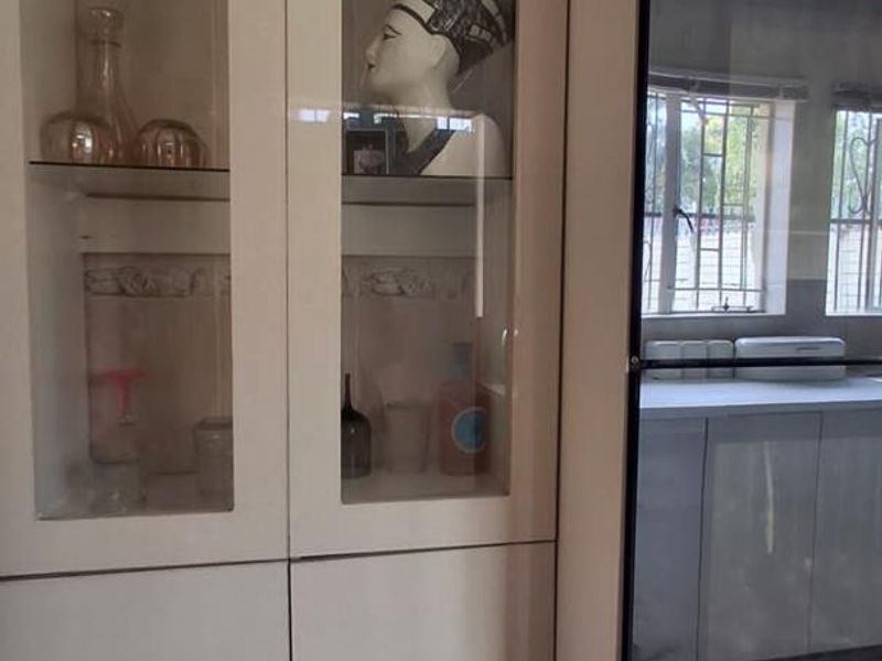 A kitchen featuring white built-in cabinetry with glass-front display sections and a modern built-in oven.