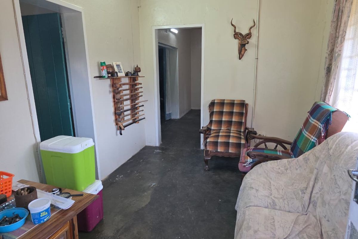 A living area featuring exposed concrete flooring, surface-mounted electrical conduit, and multiple doorways leading to adjacent rooms.