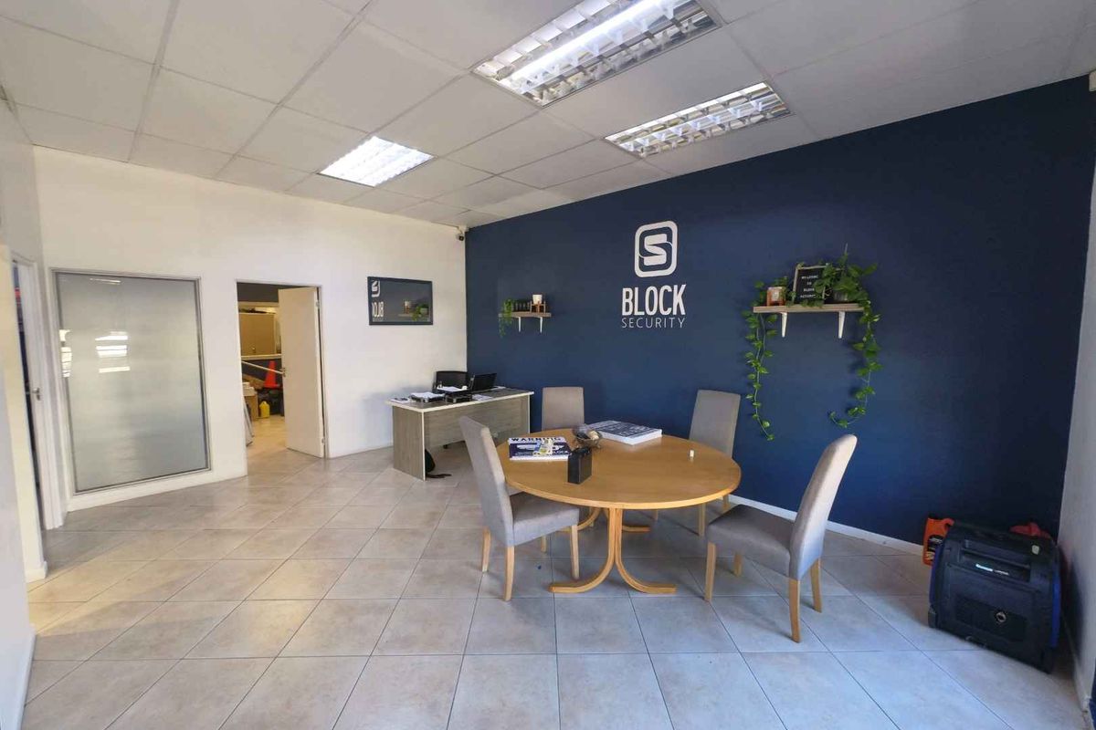 A professional office space featuring tiled flooring, a suspended ceiling with recessed lighting, and a prominent feature wall with branding.