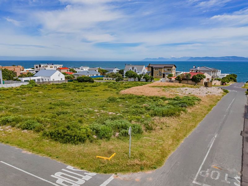 A vacant corner residential plot situated in a coastal neighborhood, offering potential for development with scenic ocean and mountain views.