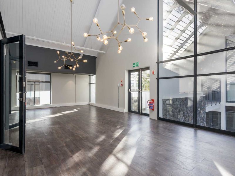 Spacious, modern office area featuring high vaulted ceilings, timber-look flooring, and expansive windows providing abundant natural light.