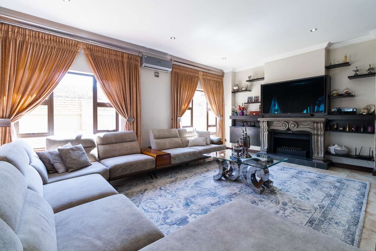 Spacious living room featuring a decorative fireplace with mantelpiece, built-in shelving, tiled flooring, and an integrated air conditioning unit.