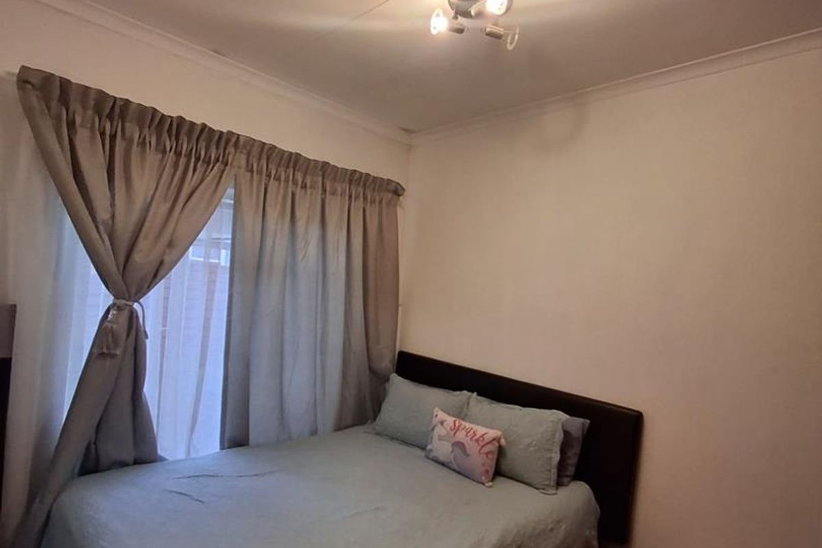 A standard bedroom featuring tiled flooring, ceiling cornice, and a central light fixture.