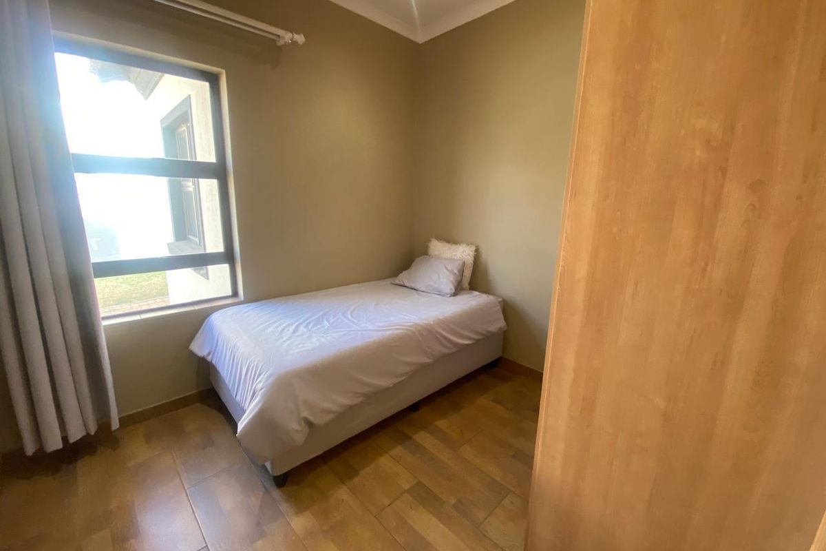 A compact bedroom featuring tiled flooring, a built-in cupboard, and a large window allowing natural light.