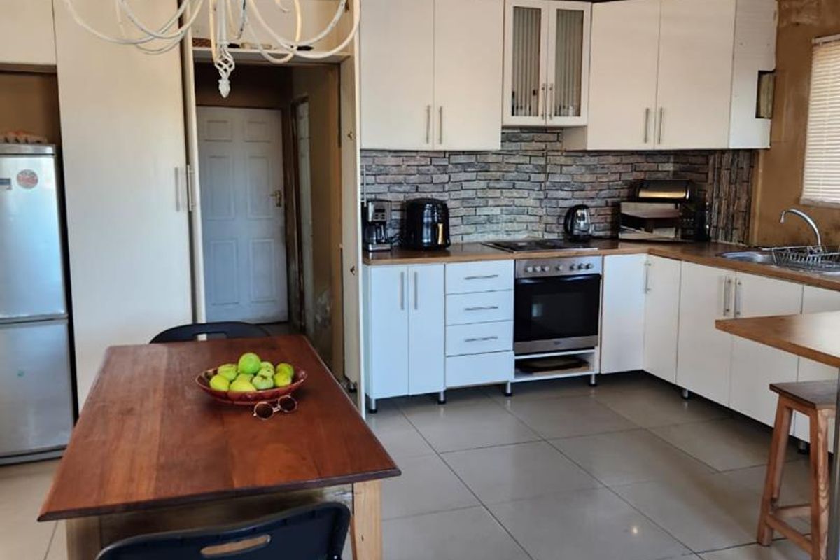 A functional kitchen featuring white cabinetry, a brick-style backsplash, built-in oven, and tiled flooring, with an adjacent dining area.