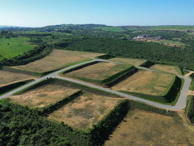 Aerial view of an industrial development site featuring leveled land platforms, established retaining embankments, and paved access roads within a green landscape.