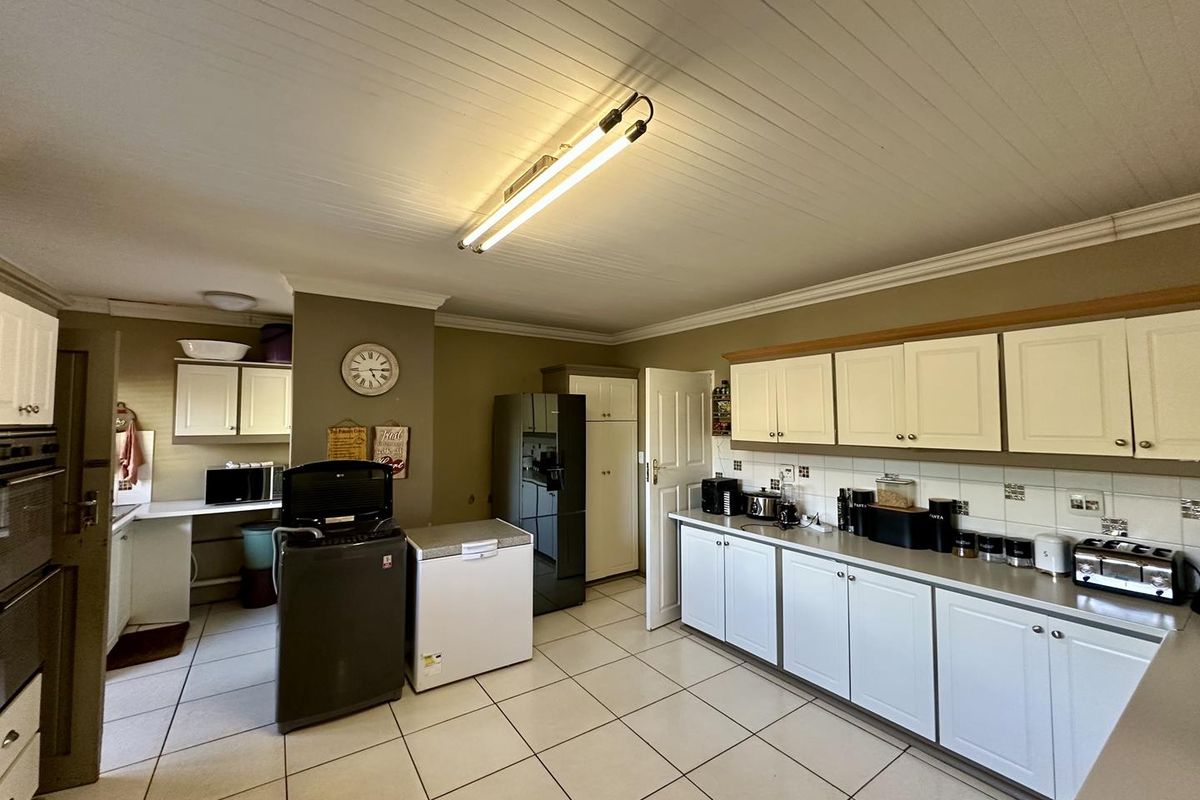 A functional kitchen featuring tiled flooring, ample built-in cabinetry, a tiled backsplash, and a tongue and groove ceiling.