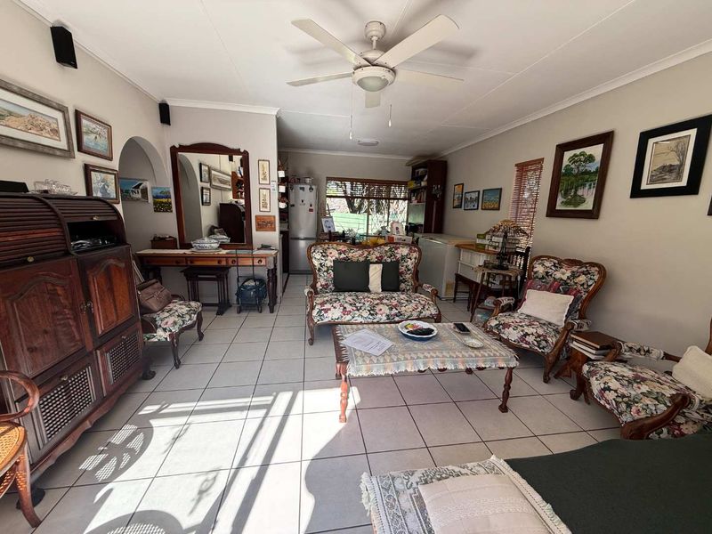 A spacious living room featuring ceramic floor tiles, a ceiling fan, and an arched entryway, offering a comfortable and functional living space.