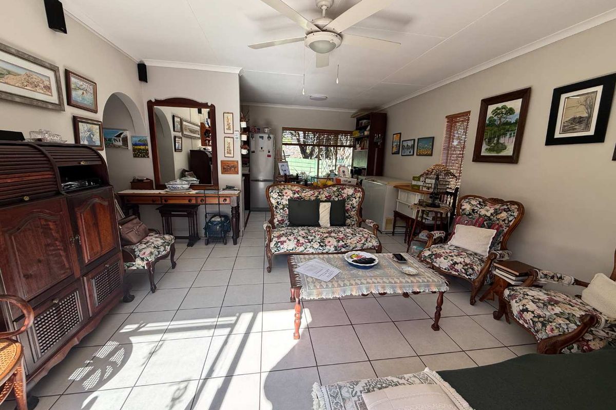A spacious living room featuring ceramic floor tiles, a ceiling fan, and an arched entryway, offering a comfortable and functional living space.