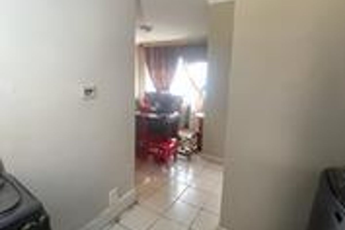 A view from the kitchen area looking through to the living space, featuring tiled flooring and neutral wall finishes.