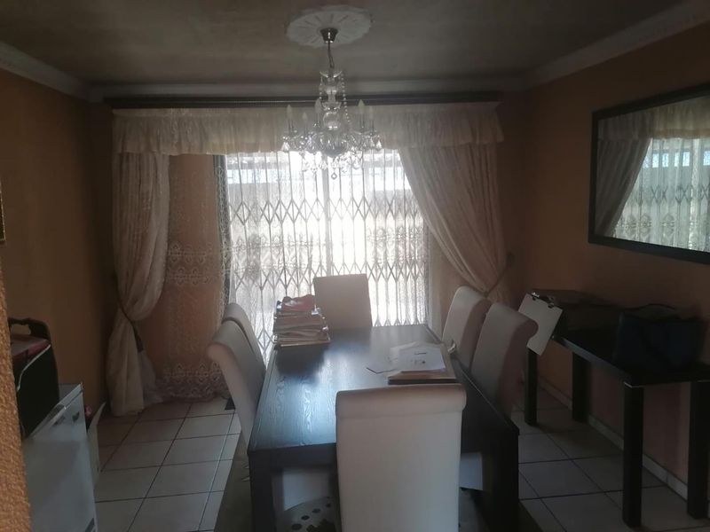 A dining room featuring ceramic floor tiles, coved cornicing, and a sliding glass door with a security gate leading to the exterior.