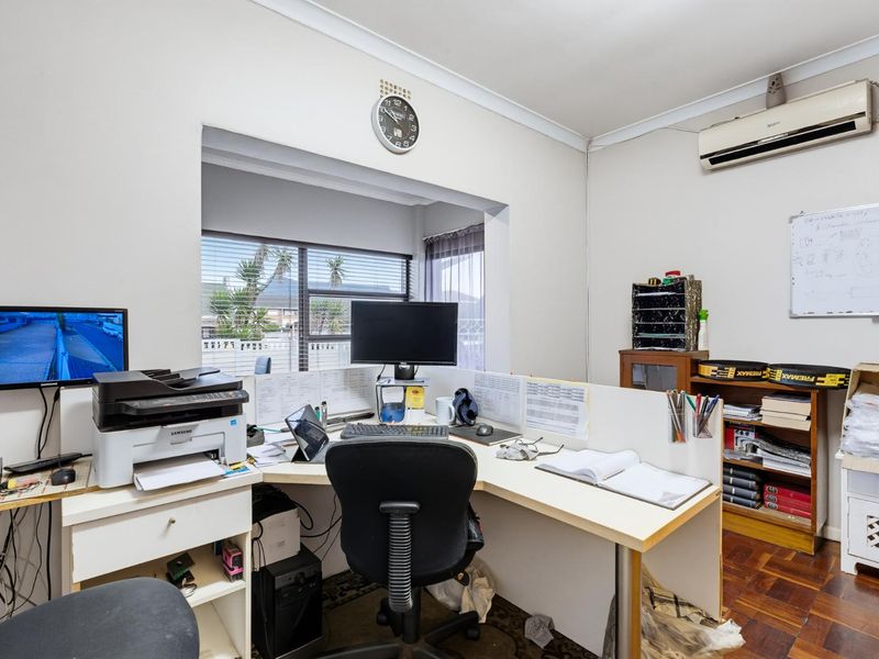 A functional home office space featuring parquet flooring, cornicing, and a wall-mounted split-system air conditioner.