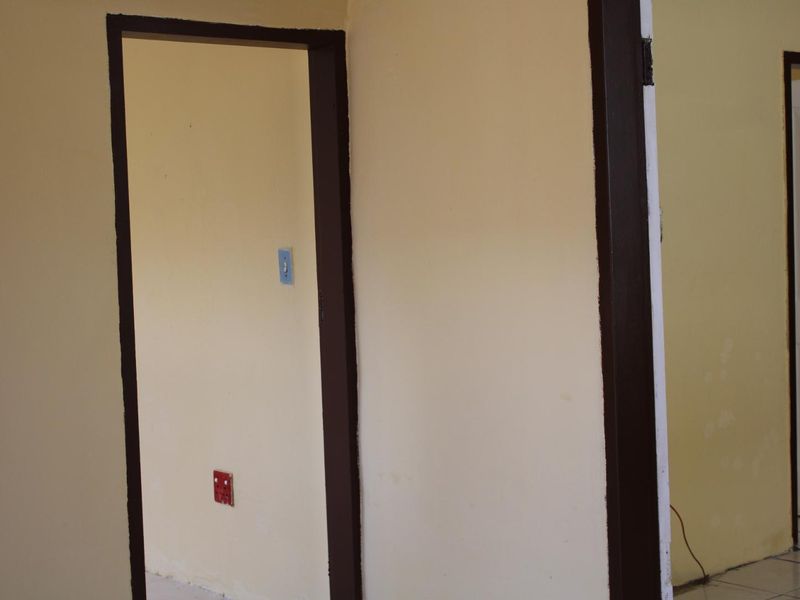 A vacant hallway featuring painted walls with dark-trimmed door frames, electrical outlets, and light switches.