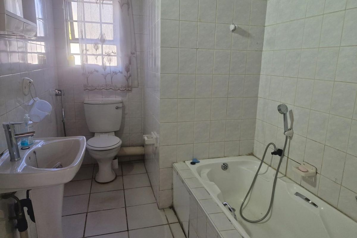 A functional bathroom featuring a pedestal basin, a standard toilet, and a built-in bathtub with a handheld shower attachment.