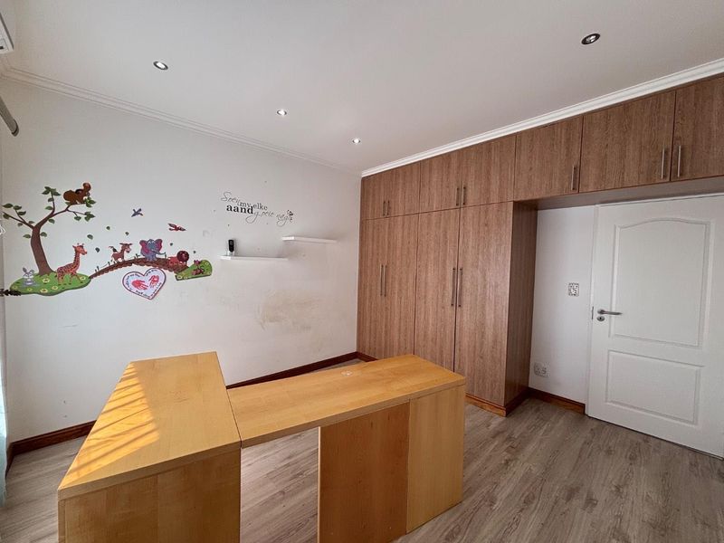 Bedroom featuring extensive built-in wooden cabinetry, recessed ceiling lighting, and durable laminate flooring, offering ample storage space.
