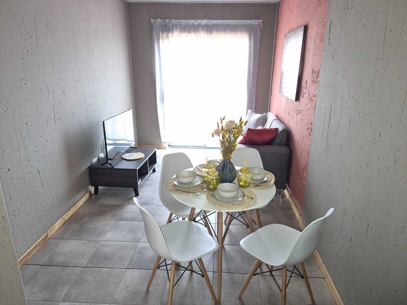 An open-plan living and dining area featuring tiled flooring, textured walls, and a sliding glass door providing natural light.