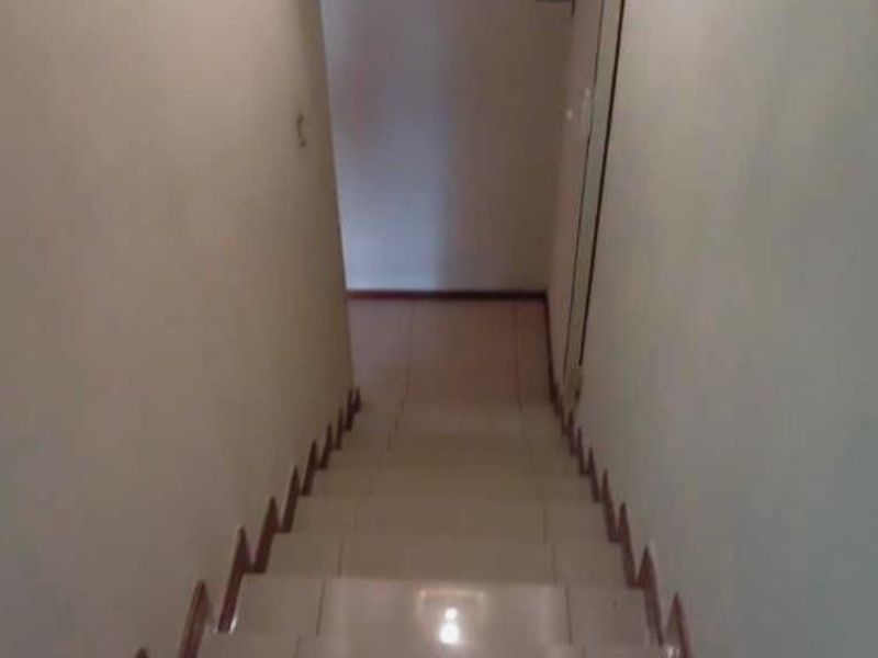 A view looking down a tiled staircase in a townhouse, featuring neutral walls and simple skirting boards.