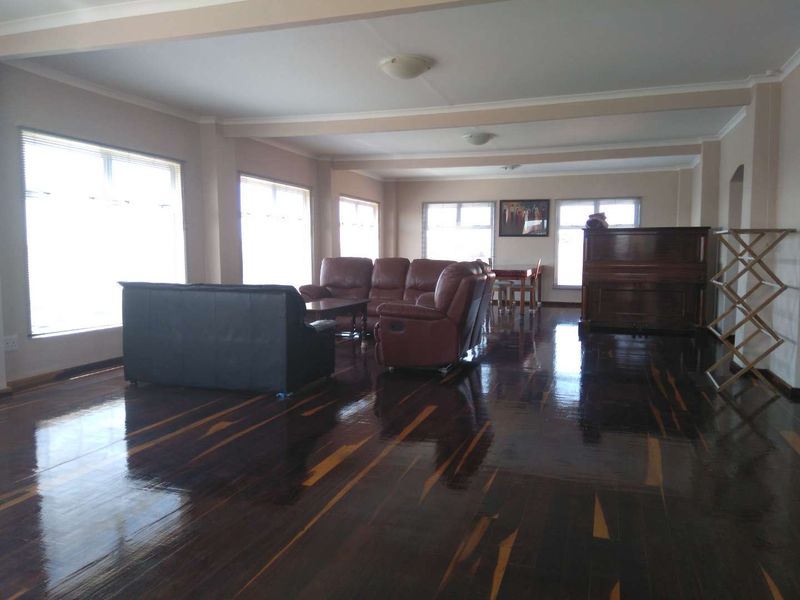Spacious open-plan living and dining area featuring polished hardwood flooring and large windows that provide ample natural light.