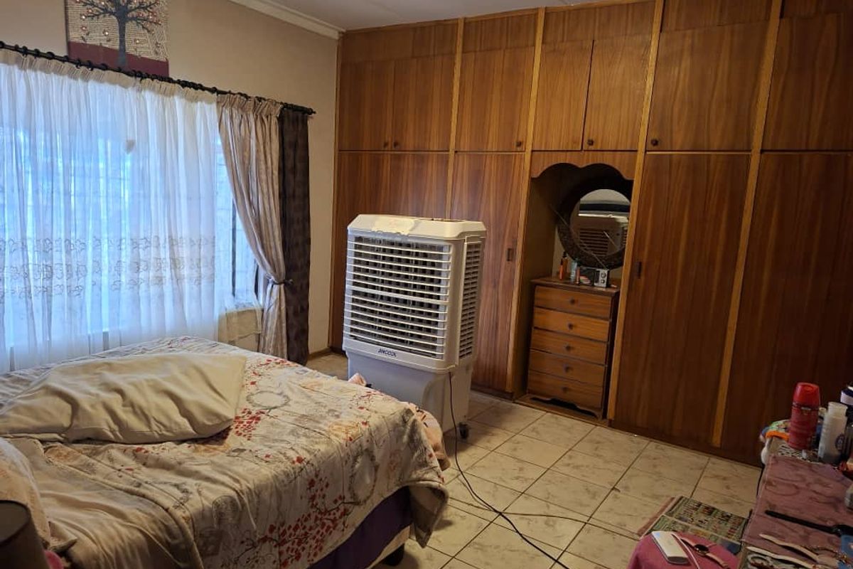A bedroom featuring extensive built-in wooden cabinetry with an integrated vanity area and tiled flooring.